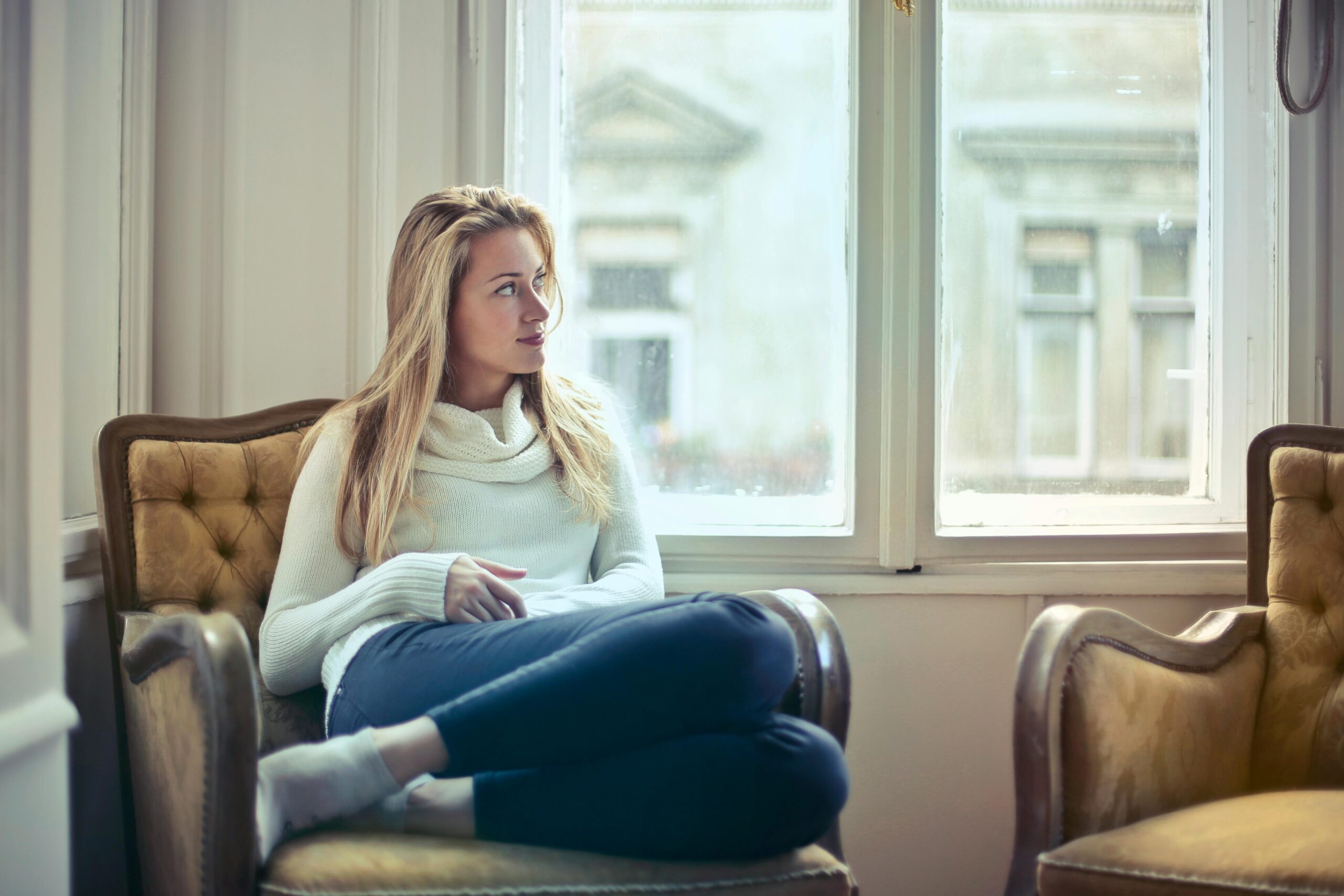 woman sitting in armchair by window